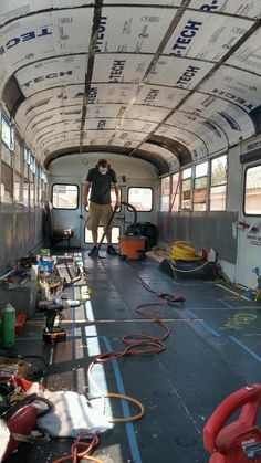 a man is standing in the back of a bus with hoses and other items