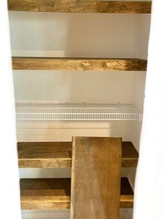 an empty pantry with wooden shelves and white tile flooring