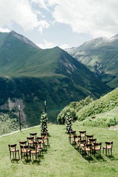 chairs are set up in the grass near mountains