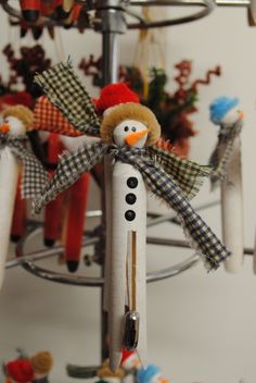 a snowman ornament is hanging from a pole with other ornaments in the background