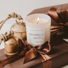 a candle sitting on top of a wrapped present box next to a brown bow and twine