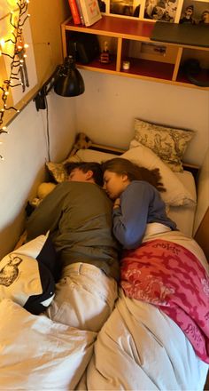 two people sleeping on top of each other in a bed