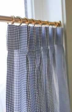 the blue and white checkered curtains are hanging in front of a window with gold hardware