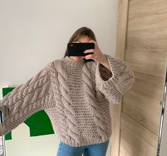 a woman taking a selfie in front of a mirror wearing a sweater and jeans