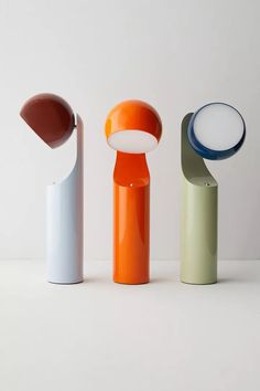 three different colored vases sitting next to each other on a white surface, one with a magnifying glass in it