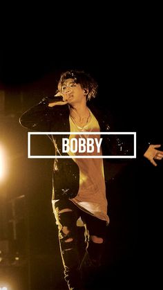 a man standing on top of a stage with his hand up to his face and the words bobby above him