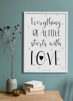 a framed poster with the words everything beautiful starts with love in black on a blue wall