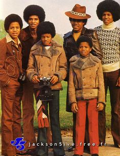 a group of people standing next to each other in front of a grass covered field