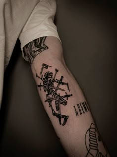 a man's arm with a skeleton and cross tattoo on the left side of his arm