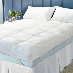 a bed with white sheets and pillows on it