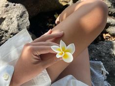 a woman's legs with a white and yellow flower on top of her arm