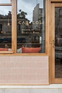 the front window of a cafe with chairs and tables