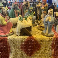 a table topped with figurines of people sitting on top of a cloth covered table