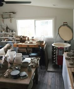 a room filled with lots of pots and pans on top of wooden tables in front of a window