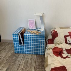 a bed room with a neatly made bed and a small blue box on the floor