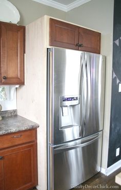 a stainless steel refrigerator in a kitchen with wooden cabinets