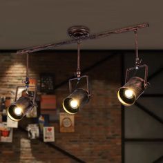 three lights are hanging from the ceiling in a room with brick walls and exposed ceilings