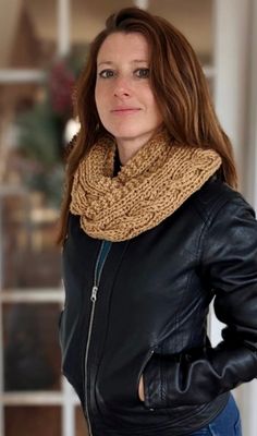 a woman wearing a black leather jacket and a brown knitted cowl neck scarf