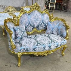 an ornate gold and blue couch sitting on top of a floor next to a table