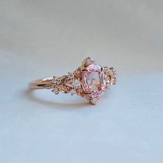 an oval shaped pink diamond ring with leaves on the band