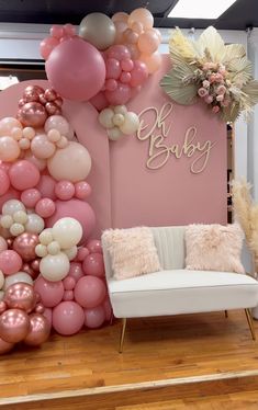 a room filled with balloons and furniture in front of a wall that says oh baby