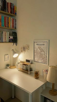 a white desk topped with a lamp next to a bookshelf