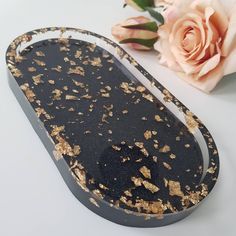 a black and gold tray next to a flower