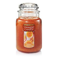 yankee candle jar filled with oranges and cinnamon on a white background, front view