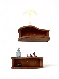 two wooden shelves with glasses on them and a lamp above one that is turned on