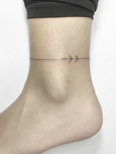 a woman's ankle with an arrow tattoo on it