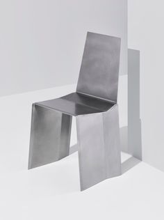 a metal chair sitting on top of a white floor next to a tall piece of furniture