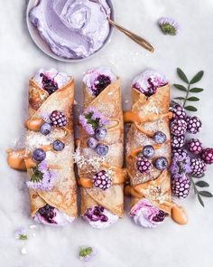 some food is laying out on a table with purple icing and flowers around it