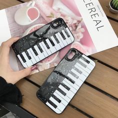 a person holding an iphone case that has piano keys on it, while sitting at a table