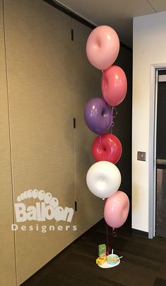 a bunch of balloons that are hanging from the ceiling in an office hallway with a door