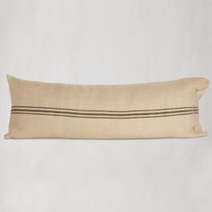 a beige pillow with black stripes on the front and back, sitting against a white wall