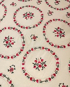 a white table cloth with red flowers and black trimmings on the edges is shown