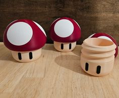 three mushroom shaped containers sitting on top of a wooden table