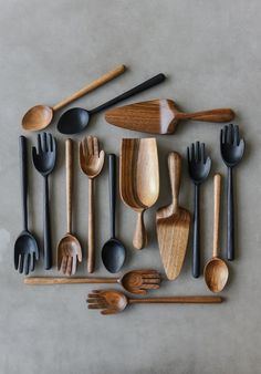 various wooden utensils and spoons arranged in a square pattern on a gray surface