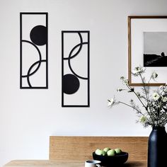 a vase filled with flowers sitting on top of a table next to two framed pictures