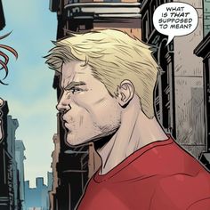 a man with blonde hair and a red shirt talking to another man in the city