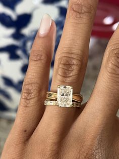 a woman's hand with two gold rings on it and a diamond in the middle