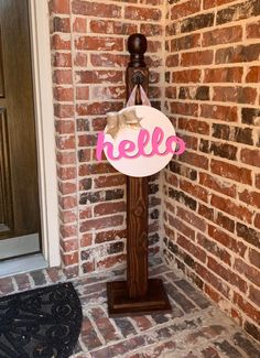 a sign that says hello on it in front of a brick wall with a door