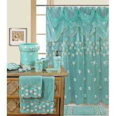 the bathroom is decorated in aqua blue and has white flowers on the shower curtain, toiletries, and rugs