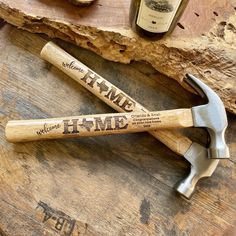 two hammers sitting on top of a wooden table next to a bottle of wine