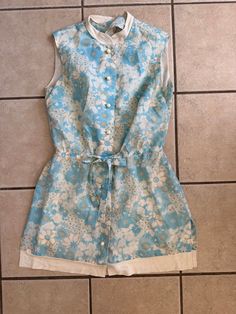 This vintage mini dress has built in shorts and a light blue and cream floral design.  It is in good condition.  It does have a stain on the back hem as shown in pictures.  It is sleeveless, has slits in the sides of the dress and a tie front with some elastic in the back at the waist. It has a tab collar and 8 buttons down the front. Some of the bottoms appear to be loose so may need to be sewn on tight. Shoulder seam to elastic waist--16 inches Waist to hem-16 inches  Chest-40 inches Hips-40 inches Waist-30 inches no pull/34 with pull Inseam-1.5 inches To see more of our authentic 1970's vintage clothing inventory please visit our store at ChoiceRecycling. We add new items every week. Thank you, Karmyn 70s Mini Dress, Vintage Mini Dress, Vintage Mini Dresses, Vintage 70s, Short Outfits, Elastic Waist, Vintage Outfits, The Dress, Floral Design