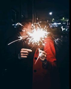 a person holding sparklers in their hands at night