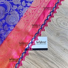 three pieces of purple and pink sari on wooden table with business card in front