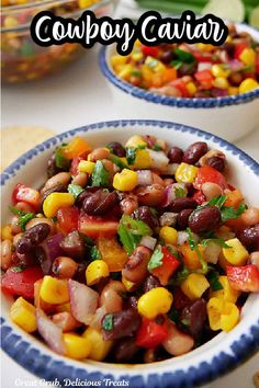 two bowls filled with black beans, corn and cilantro on top of a table