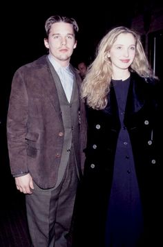 a man and woman standing next to each other in front of a dark room with people