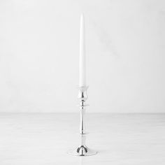 a single white candle sitting on top of a table